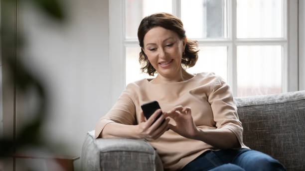 istock Smiling mature woman texting on smartphone at home 1247334238