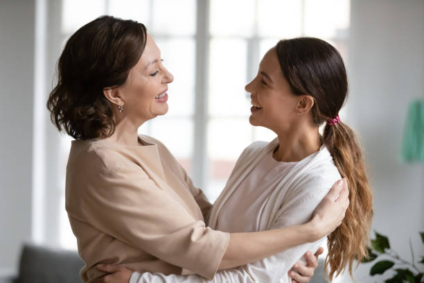 istock Smiling middle-aged mom and grownup daughter hugging at home 1247334248
