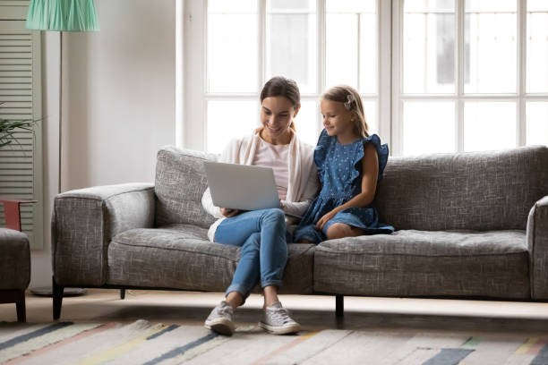 istock Happy mother and little daughter relax on couch using laptop 1247334258