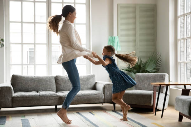 istock Happy mom and small daughter dancing jumping at home 1247334274