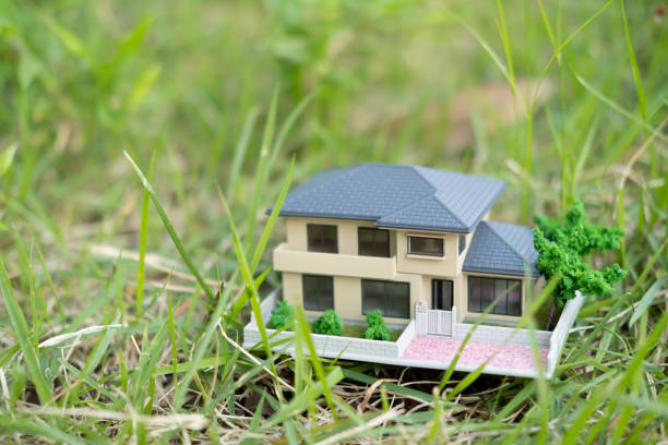 A small ceramic house with a red roof standing on a cobblestone in the garden