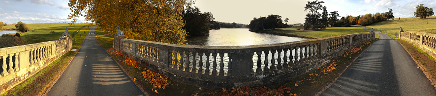 wide panoramic panorama image of country road crossing an ornate bridge- warwickshire midlands england uk