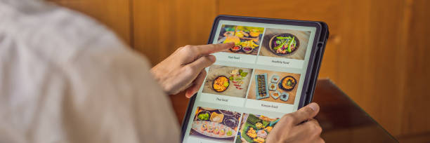 istock man orders food for lunch online using Tablet BANNER, LONG FORMAT 1247429157