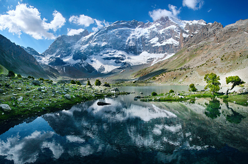 Picturesque lake in the mountains of Tajikistan. Snow-capped peaks are reflected in the water. Travels in Central Asia.