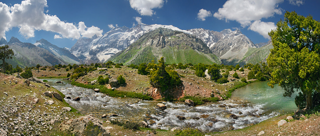 Tourism in Tajikistan, valley in the Fan Mountains, panorama nature. Mountain river, snow-capped peaks.