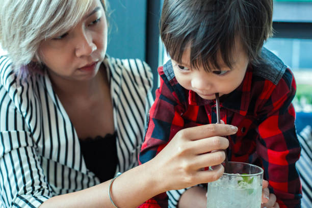 istock sigle mom help child drinking water from straw between working. 1247502270