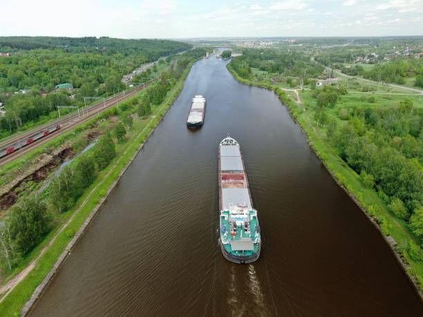 istock Beautiful panoramic landscape from high altitude two cargo commercial ships sail down the river on counter courses surrounded by green forest in summer with a sunny day 1247528876