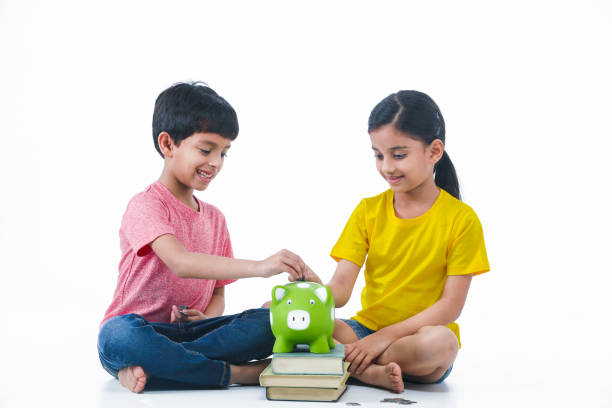 Kid Boy & Girl putting penny, money in pig shape piggy bank Indian, Asian Kid Boy & Girl putting penny, money in pig shape piggy bank for future education with books dealing room photos stock pictures, royalty-free photos & images