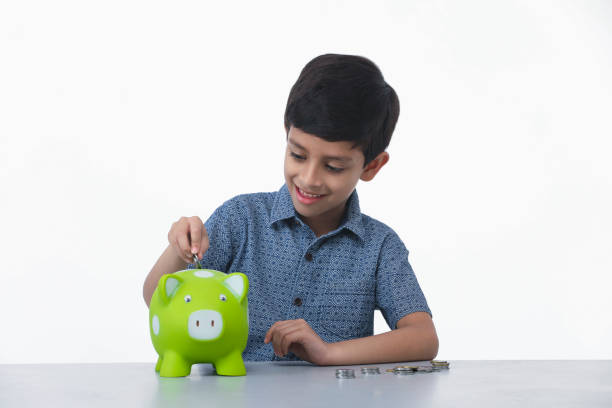 Kid boy saving money by putting it in pig shape piggy bank, smiling, hugging and thinking Indian, Asian Kid 6-7 years boy saving money by putting it in pig shape piggy bank, smiling, hugging and thinking dealing room photos stock pictures, royalty-free photos & images