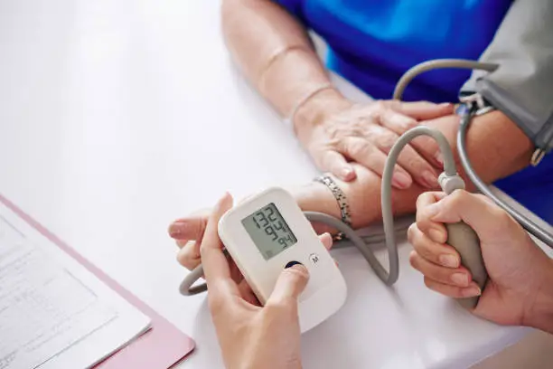 Close-up image of doctor measuring blood pressure of elderly woman during annual check-up
