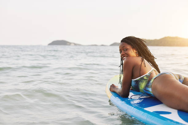istock Black woman swimming on surfboard 1247605497
