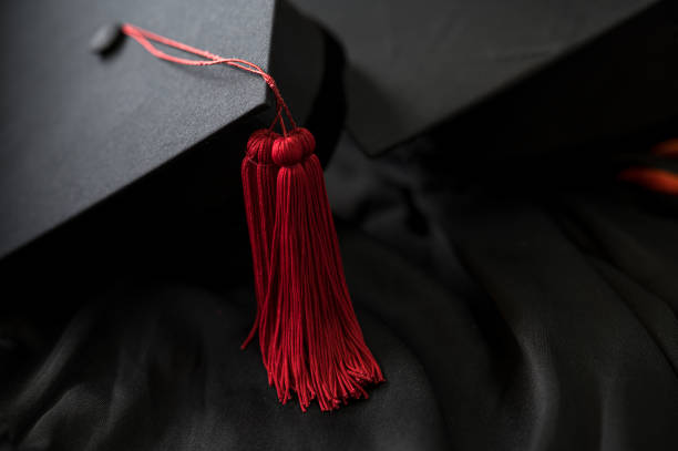 closeup, black graduated hat and red tassel placed on a black frilly outfit