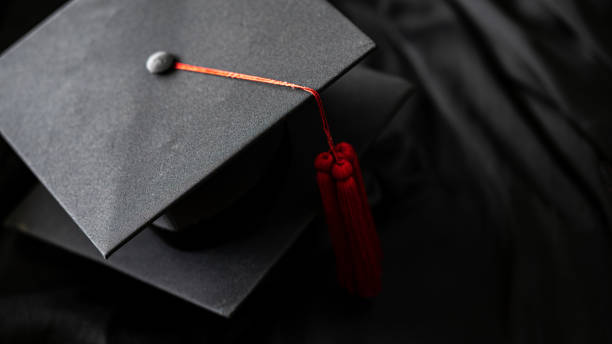 istock closeup, black graduated hat and red tassel placed on a black frilly outfit 1247634764