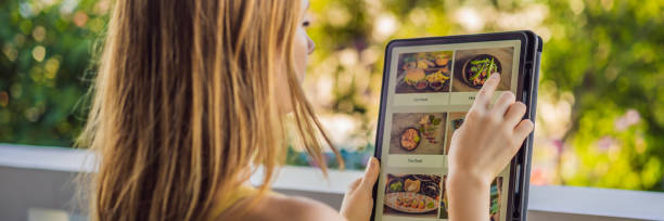 istock Young woman orders food for lunch online using Tablet BANNER, LONG FORMAT 1247642199
