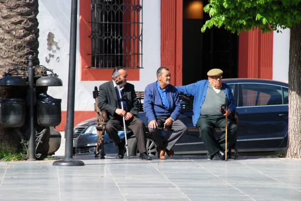 Spanish men on a bench, Carmona, Spain. Elderly Men sitting in the Plaza de San Fernando, Carmona, Seville Province, Spain,Europe. carmona stock pictures, royalty-free photos & images