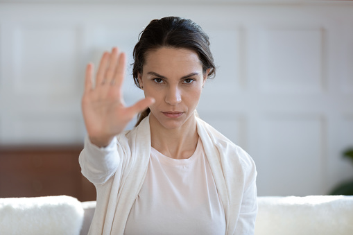 Portrait of confident young Caucasian woman show stop gesture sign against domestic violence or abuse, determined millennial girl protest against gender discrimination, nonverbal language concept