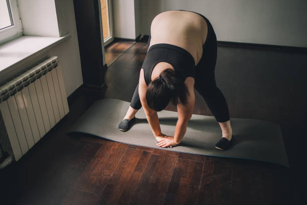 istock overweight woman doing stretching exercise at home 1247651840