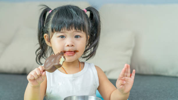 little girl eating ice-cream Dirty-faced little girl eating chocolate ice-cream. asian little chinese girls eating ice cream stock pictures, royalty-free photos & images