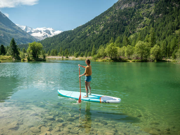 stand up paddle with a view, woman on sup in the mountains looking at glacier - switzerland lake mountain landscape imagens e fotografias de stock