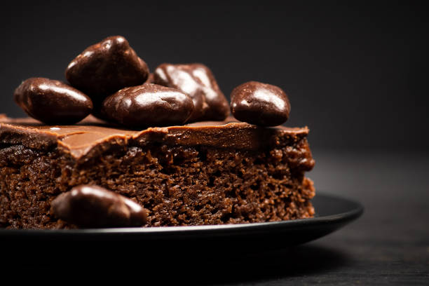 Delicious chocolate cake in dark plate on wooden table closeup