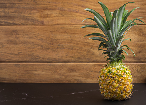 Whole of Pineapple on a table with wooden background.