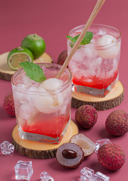 Lychee juicy punch drink Lychee juicy punch drink with mint in glass on wooden board and pink background. lychee stock pictures, royalty-free photos & images