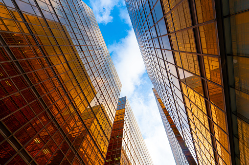 Low wide-angle view looking up to modern skyscrapers in business district on a beautiful sunny day with blue sky