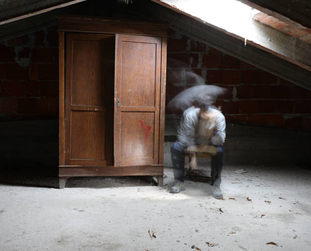 ghost of a man sitting on the chair in the attic with the old cl ghost of a pensive man sitting on the chair in the dusty attic with the old closet interior of old house garret stock pictures, royalty-free photos & images