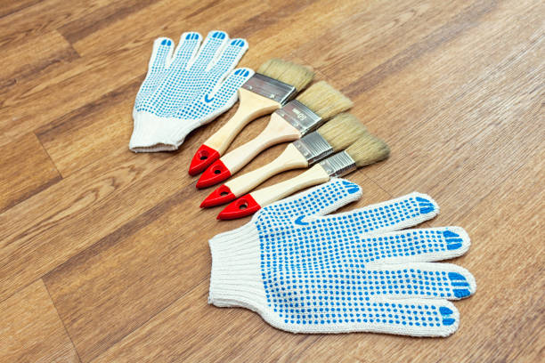 Composition from painting tools with paint brushes, gloves and paint roller on the wooden background