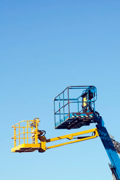 istock Two tall cherry pickers, clear blue sky background. 1247690078