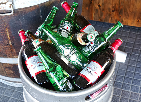 Kaohsiung, Taiwan -- June 2, 2019: A food stall prepares beer bottles in an aluminum barrel.