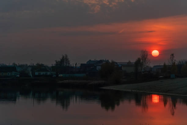 hermosa puesta de sol de color rojo anaranjado con el sol en el lago en la parte de la ciudad, hay un ventilador de viento cerca - romantic sky audio fotografías e imágenes de stock