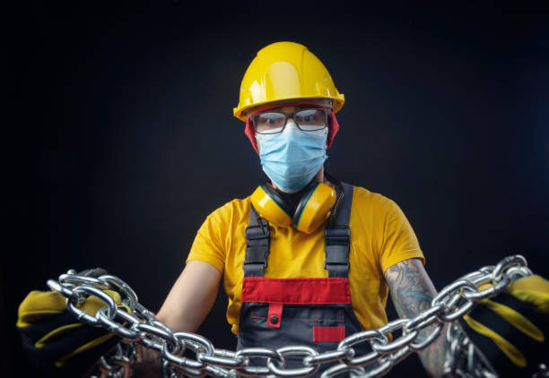 człowiek w kombinezonie naprawy budowlanej z maską medyczną przeciwko koronawirusowi trzyma metalowy łańcuch w rękach - sex symbol audio zdjęcia i obrazy z banku zdjęć