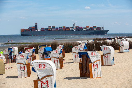 Cuxhaven, 3 June 2010. Container vessel ‚Paris Express‘ is passing Cuxhaven on the river Elbe en route to Hamburg. PARIS EXPRESS (IMO: 9447902) is a Container Ship that was built in 2011 and is sailing under the flag of Liberia. The carrying capacity of the vessel is 12600 TEU. Her overall length (LOA) is 366.06 meters and her width is 48.23 meters. At the front there is the beach of Cuxhaven with many beach chairs for the tourists. Vessels entering the river Elbe passing close to the beach and port of Cuxhaven on their way to and from Hamburg.