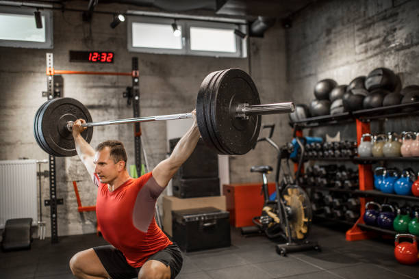 istock Mature strong man lifting weights at cross training in gym. Bodybuilder doing squatting with a barbell. 1247728023