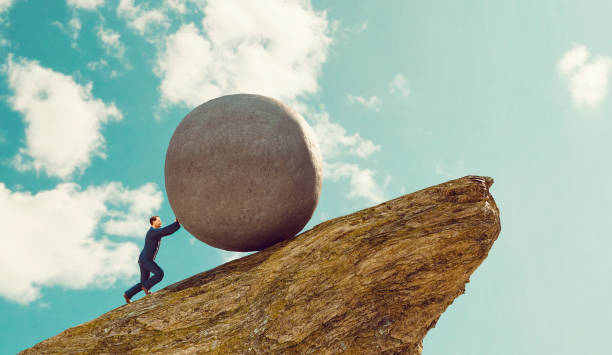 Concept of hard work for businessman pushing rock up a hill Concept of business work. Man stands on a hill and uses his strength to push a big rock up the steep hill side. Pushing a rock up hill is also a reference to the greek mythology Sisyphus ot Sisyphos.
Note: The man is a 3D-render with face scan. Model release attached. toughness stock pictures, royalty-free photos & images