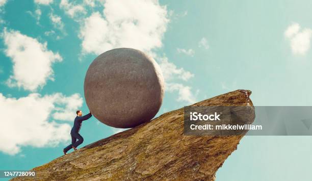 Concept Of Hard Work For Businessman Pushing Rock Up A Hill Stock Photo - Download Image Now