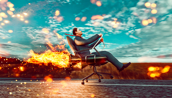 Concept of business growth and success. Man wears business suit and sits in an office chair which is connected to two rockets. He drives the office chair fast on a road and almost takes off.
Note: The man is a 3D-render with face scan. Model release attached.