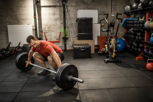 istock Mature strong man lifting weights at cross training in gym. Bodybuilder doing squatting with a barbell. 1247728198