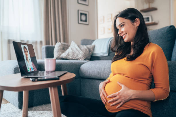 femme enceinte ayant l’appel vidéo avec le docteur - one person women human pregnancy beautiful photos et images de collection