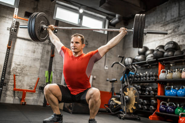 istock Mature strong man lifting weights at cross training in gym. Bodybuilder doing squatting with a barbell. 1247729407