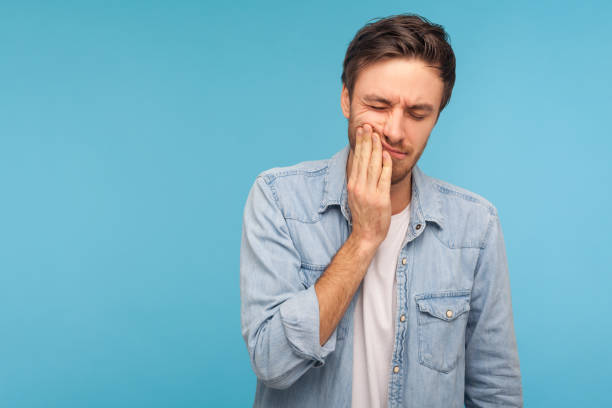 zahnprobleme. porträt eines ungesunden mannes in jeanshemd drücken wunde wange, leiden akute zahnschmerzen - dentist pain human teeth toothache stock-fotos und bilder