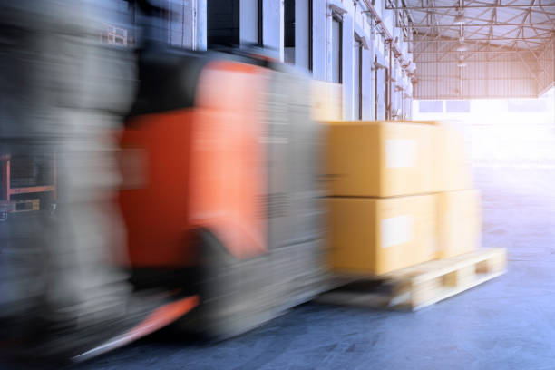 istock Speed motion blur of forklift driver unloading shipment pallet goods at the warehouse.. 1247733197