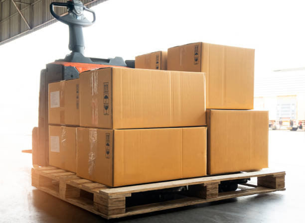 istock Electric forklift pallet jack unloading shipment boxes at the warehouse. 1247733249