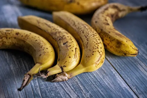 group of ripe bananas on the wooden table - closeup