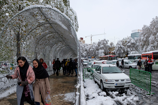 This is a sidewalk in uptown Tehran beside Tajrish square. Persian women wearing a hijab, passing through a tunnel in order to reach the bus station and use public transportation to commute.