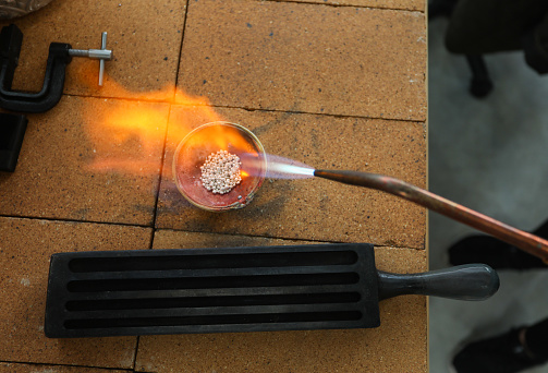 A close up shot of a blow torch melting silver to be used for a ring.