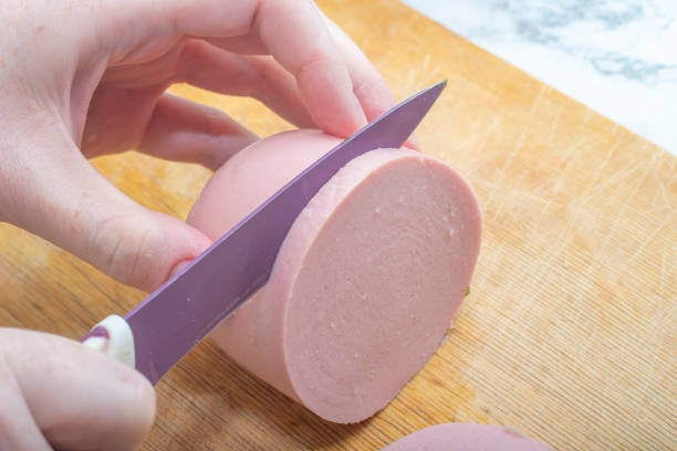 istock Close-up - hands cut soft pink sausage with a knife 1247744108