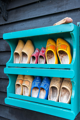 Rack with a collection of wooden shoes in various sizes and colors hanging on a wall