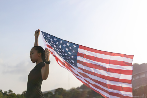 A Young asian woman holding American flag on blue sky background